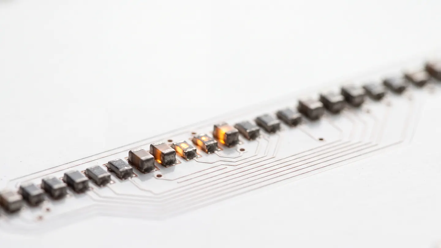 A single row of tiny components on a white board, three of them glowing